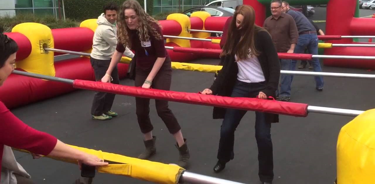 Adults playing inflatable human foosball outdoor
